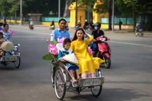 The Old Quarter Vietnamese girl wears traditional long dress Ao Dai going by Cyclo pedicab on Hanoi street